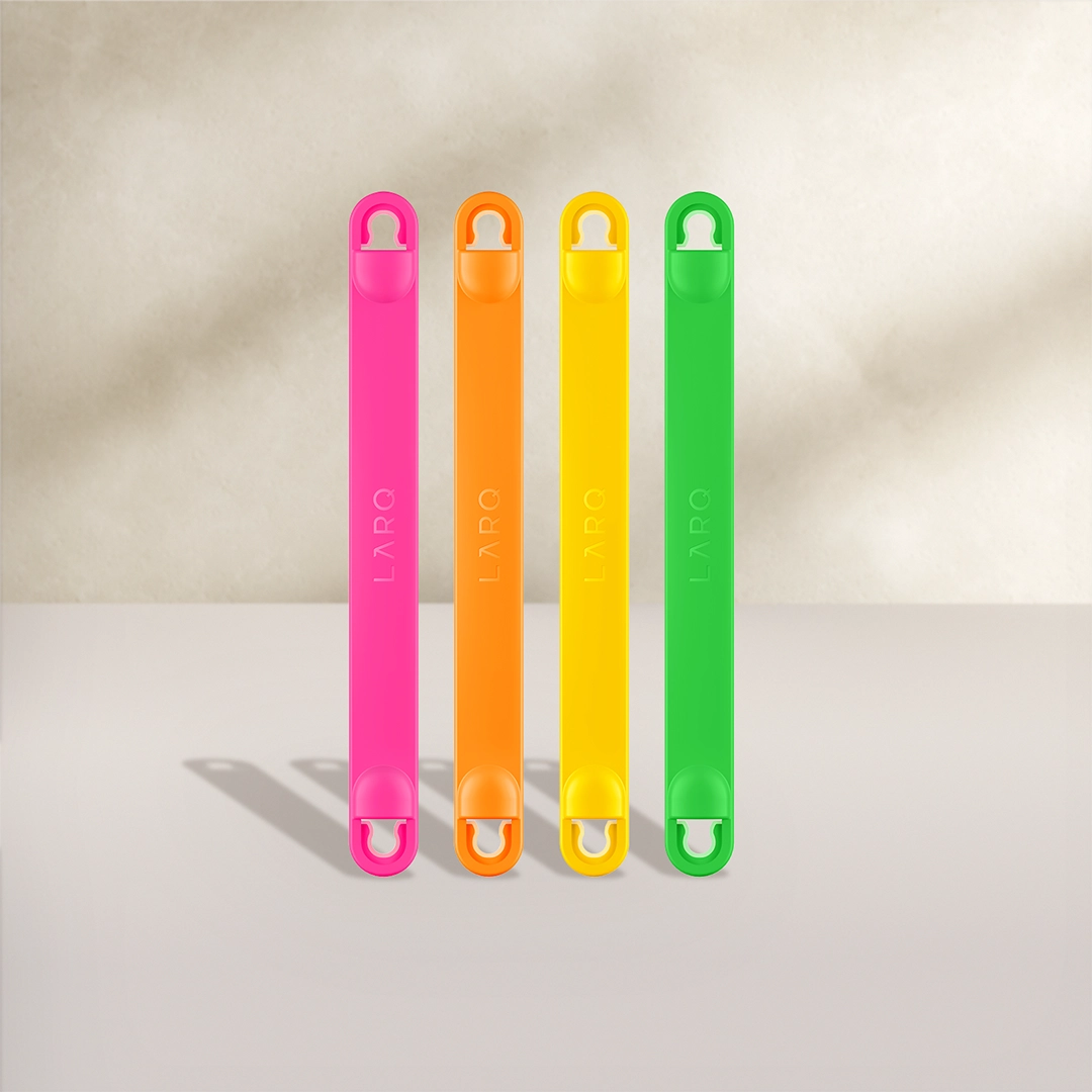 Asas para botellas BRITA LARQ en cuatro colores: rosa, naranja, amarillo y verde sobre un fondo beige.
