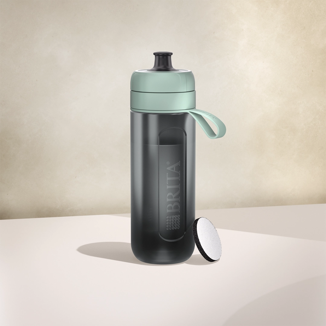 Botella filtrante BRITA Active de color verde oscuro sobre un fondo beige
