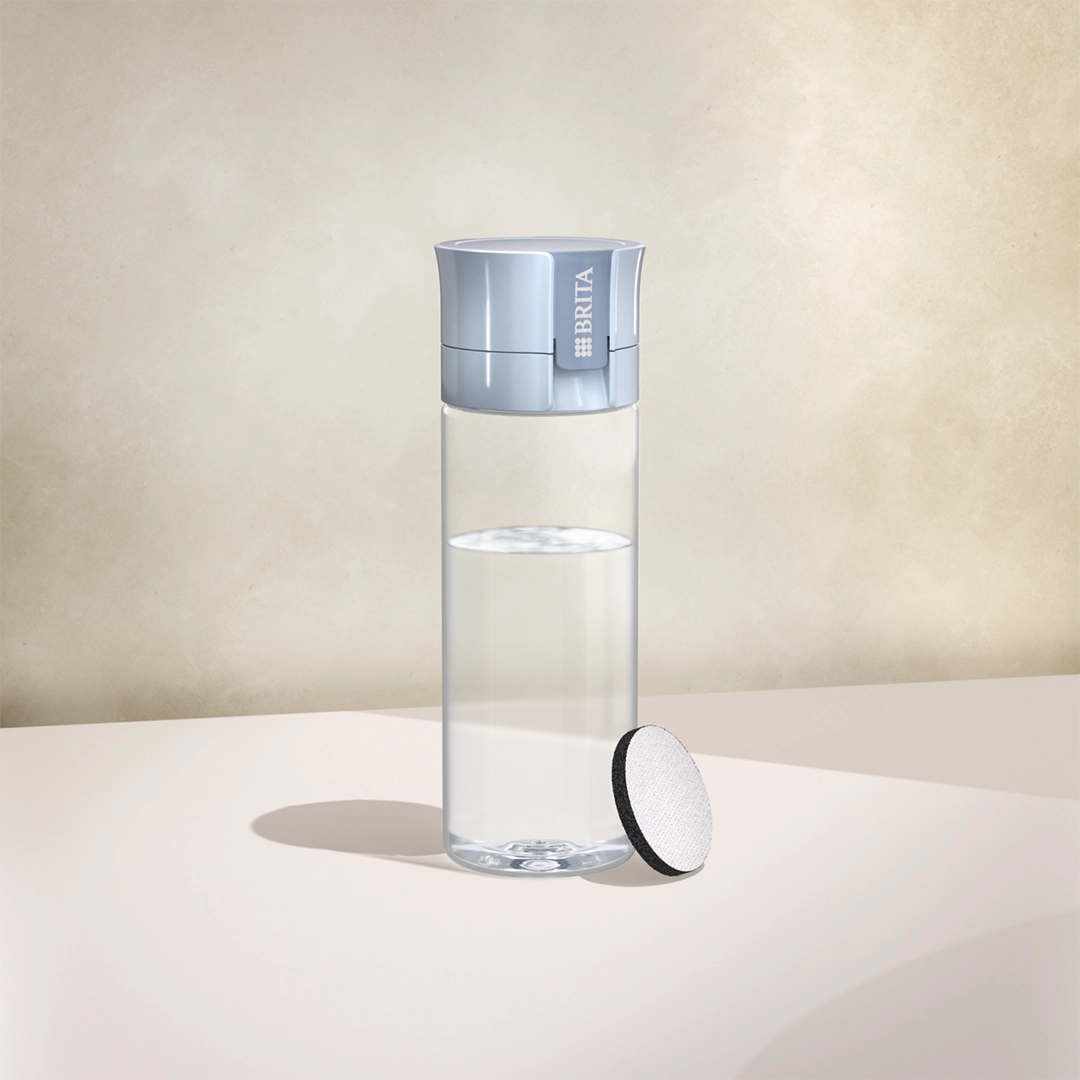 Botella filtrante BRITA Vital en azul claro sobre fondo beige