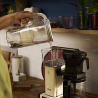 Pouring water with BRITA glass jug in grey in a coffee maker.
