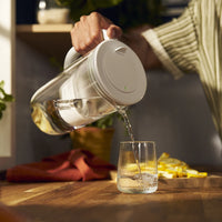 Pouring water in a glass with BRITA glass jug in grey.