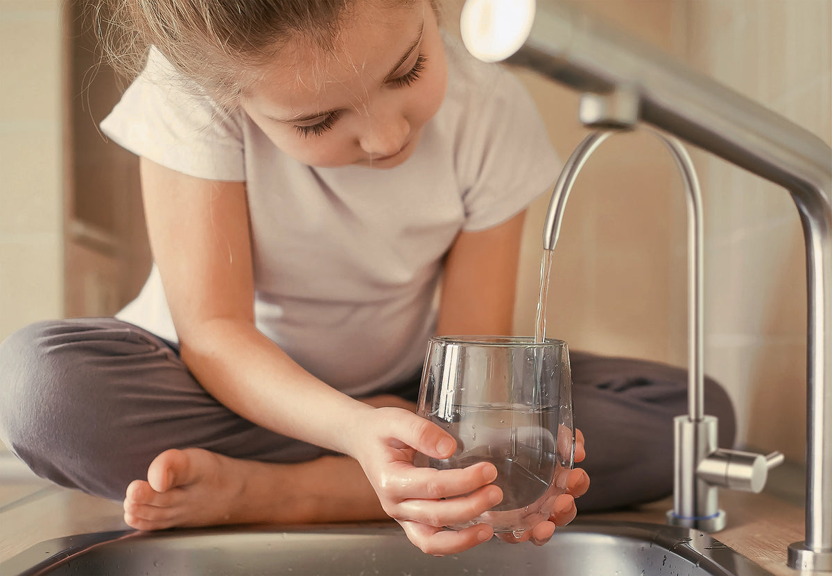 Child filling a drinking glass with filtered water from a BRITA mypure RO.